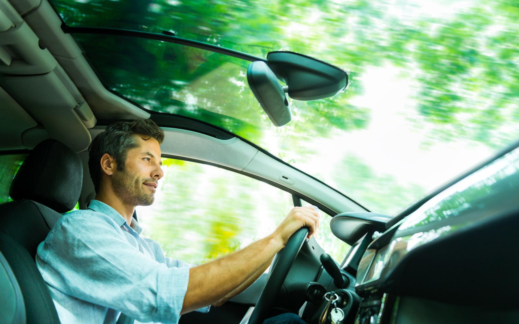 Mann som sitter i førersetet og kjører bil