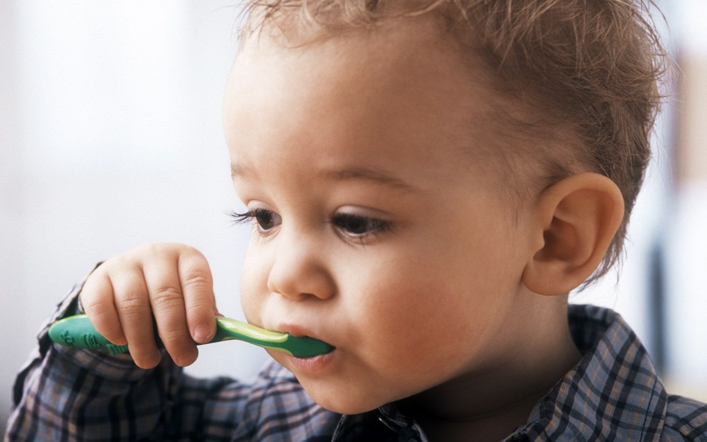 Barn med en plastskje i munnen