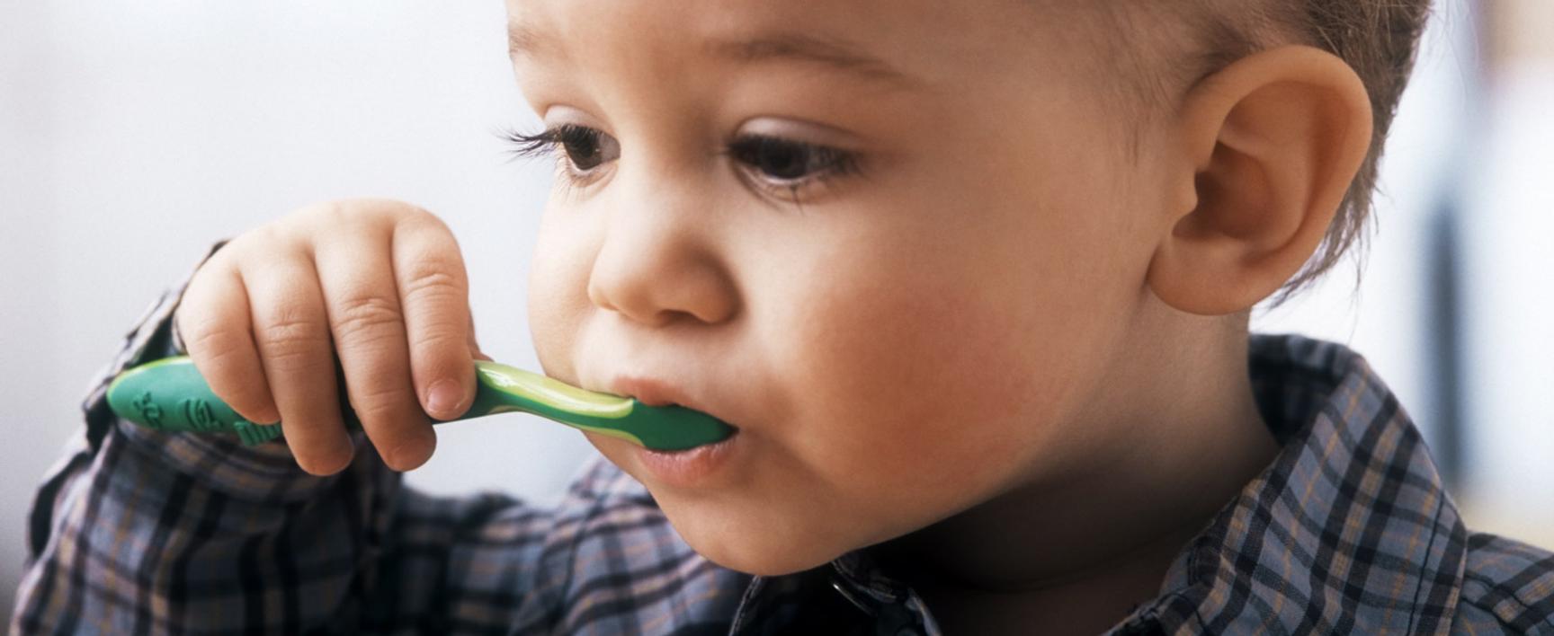 Barn med en plastskje i munnen