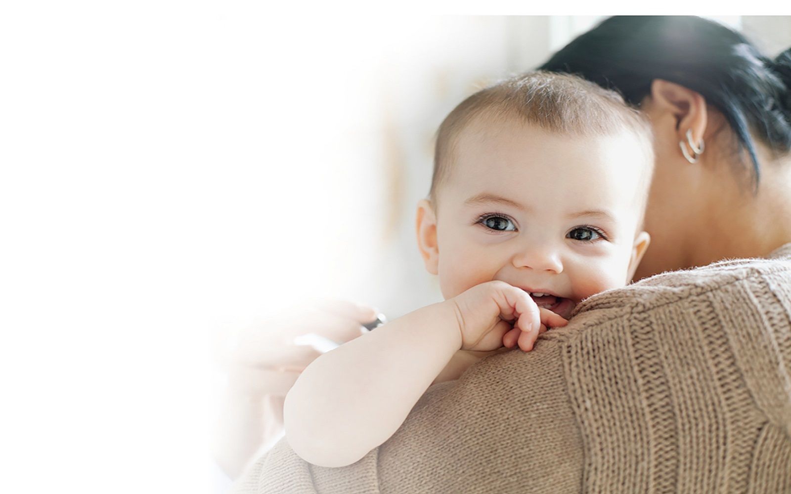 En dame som holder en baby som lener seg mot skulderen