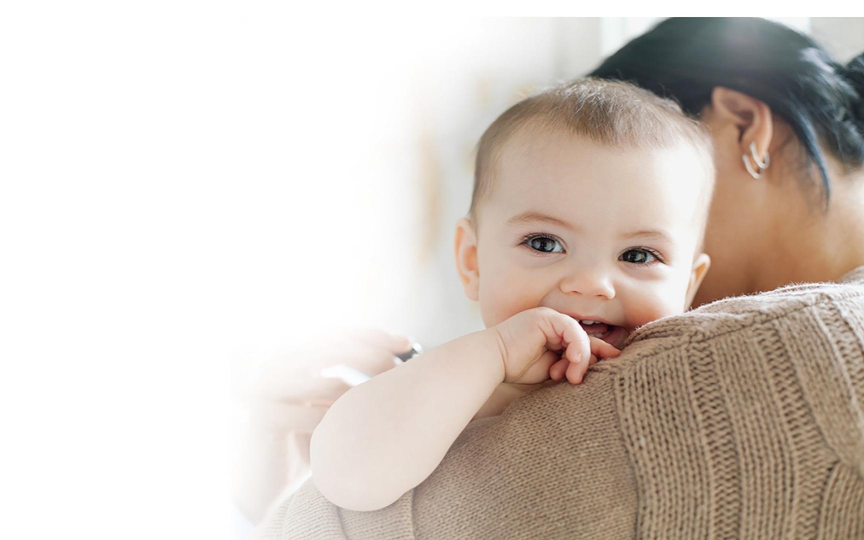 En dame som holder en baby som lener seg mot skulderen