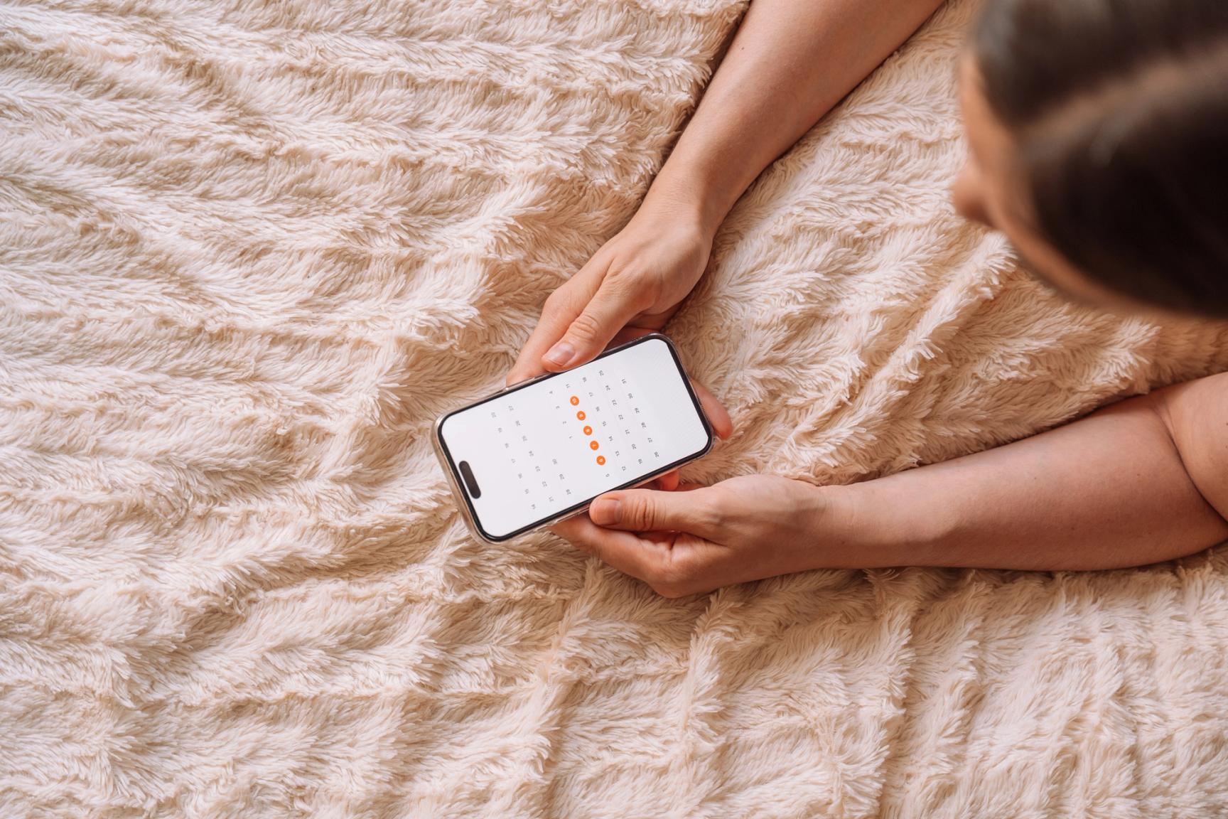 En kvinne holder en telefon i hånden med en kalender