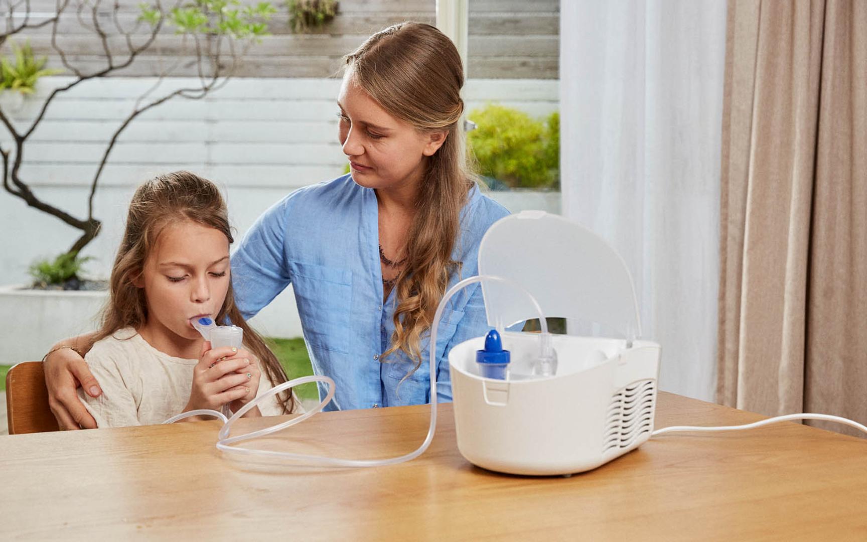 En voksen hjelper en pike å inhalere via et forstøverapperat.