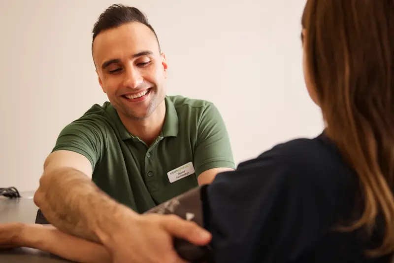 Farmasøyt smiler og sjekker blodtrykket på kunde 