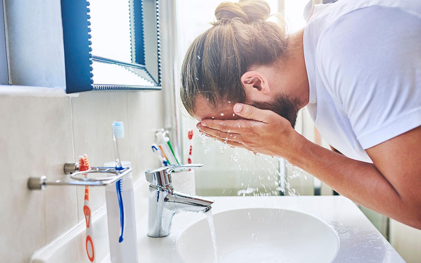 En mann vasker ansiktet sitt på et bad