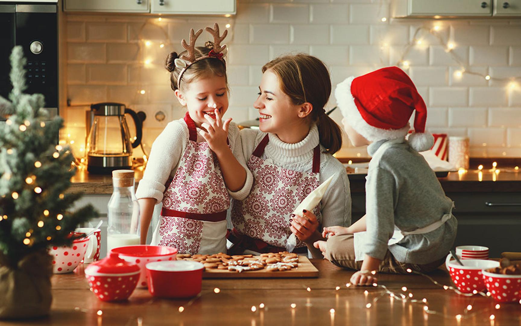 Mor med 2 små barn som smiler mens de baker pepper kaker på kjøkkenet