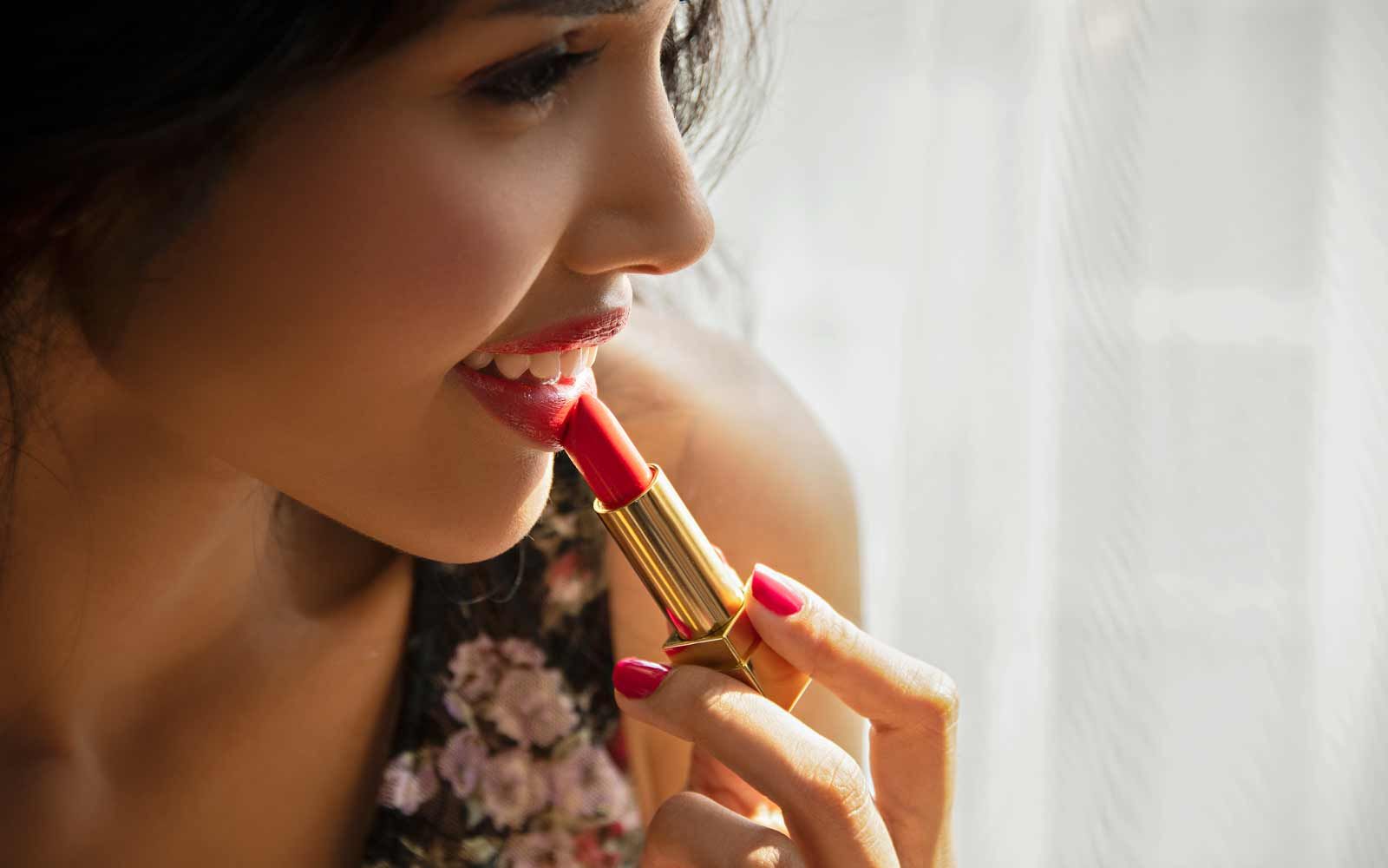 Bilde av en kvinne som tar på rød leppestift. 