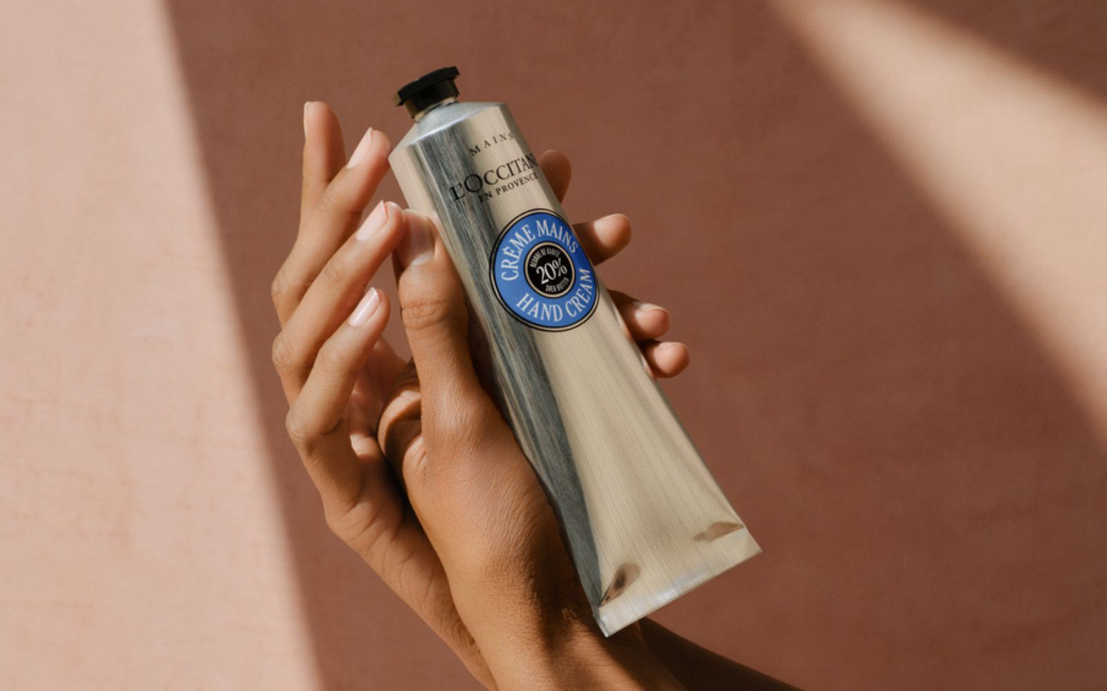 Hender som holder en l`occitane kremtube