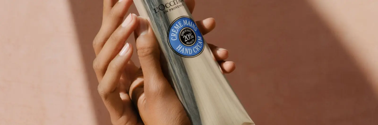 Hender som holder en l`occitane kremtube