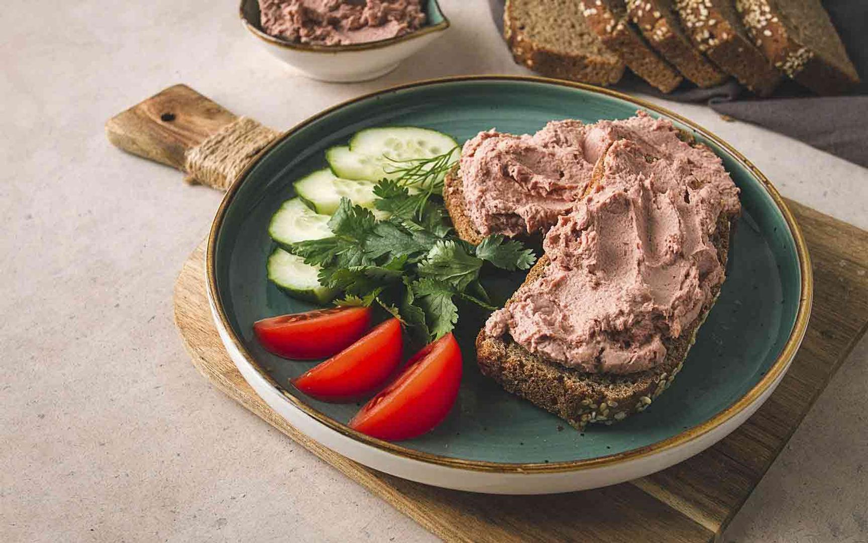 To brødskiver med leverpostei ligger på en tallerken