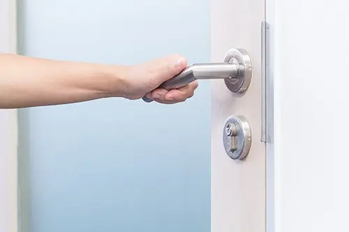 Hånd på dørhåndtak