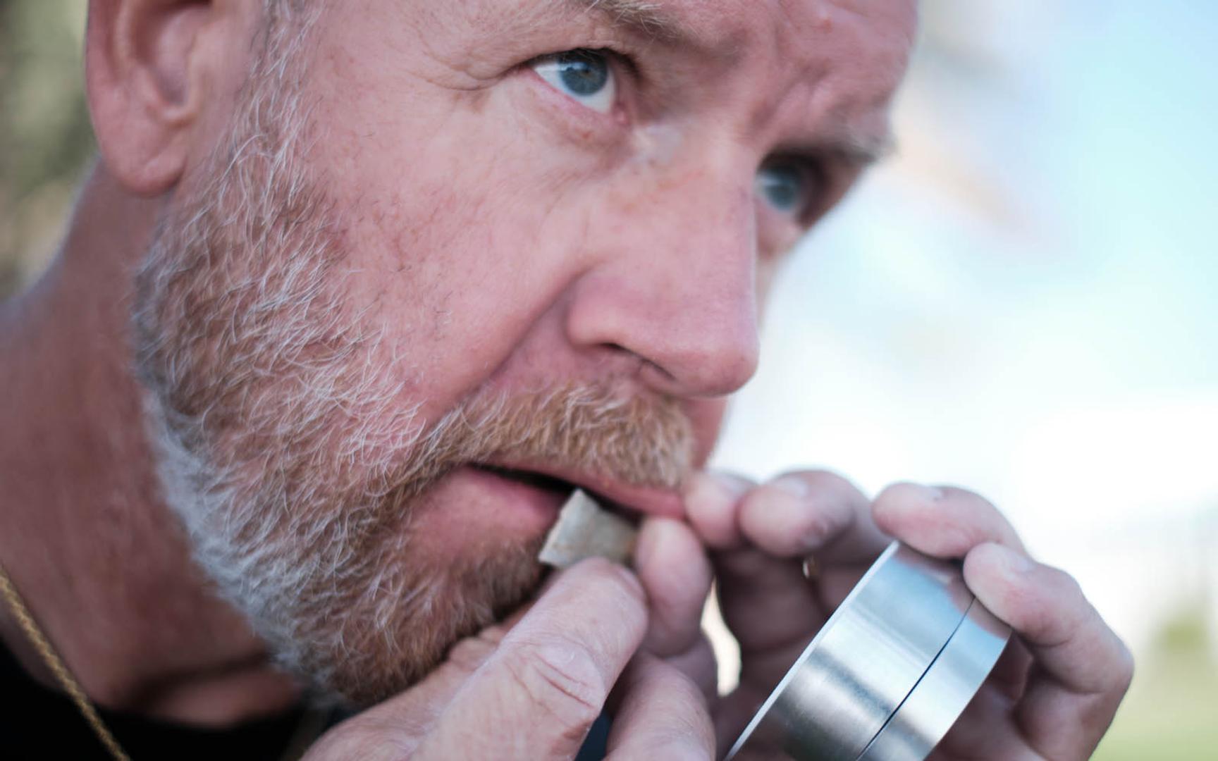 Mann legger porsjonssnus under overleppen