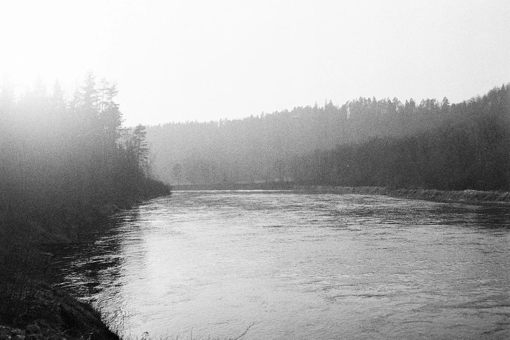 Black and white photo of a river against sun.