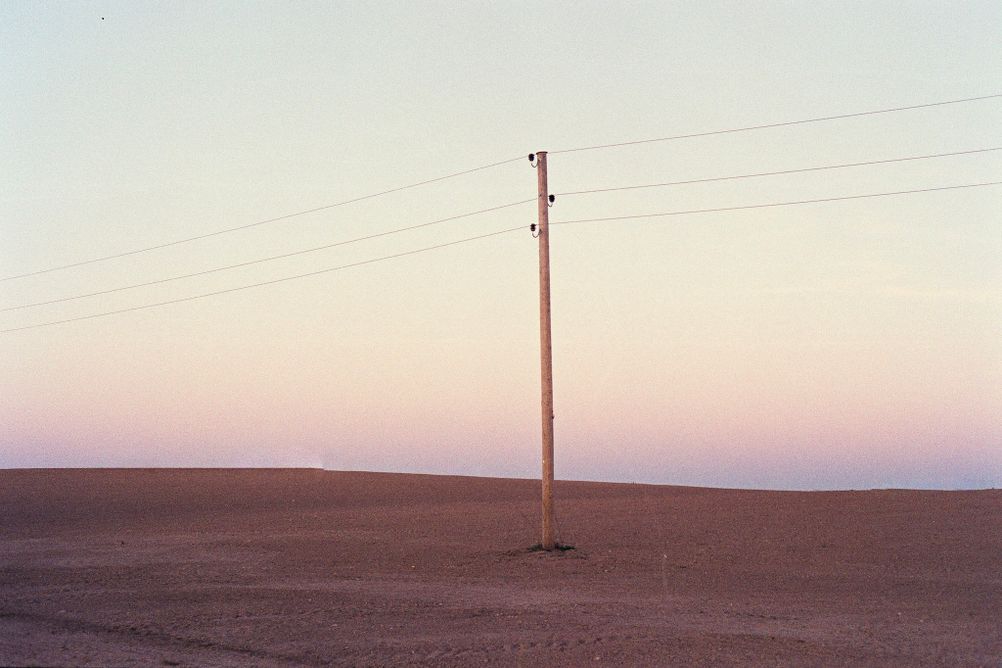 Photo of a single electricity pole in a brown field.