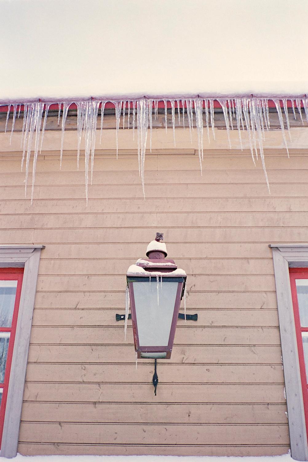 Closeup of a house with window corners, lamp and frozen water.