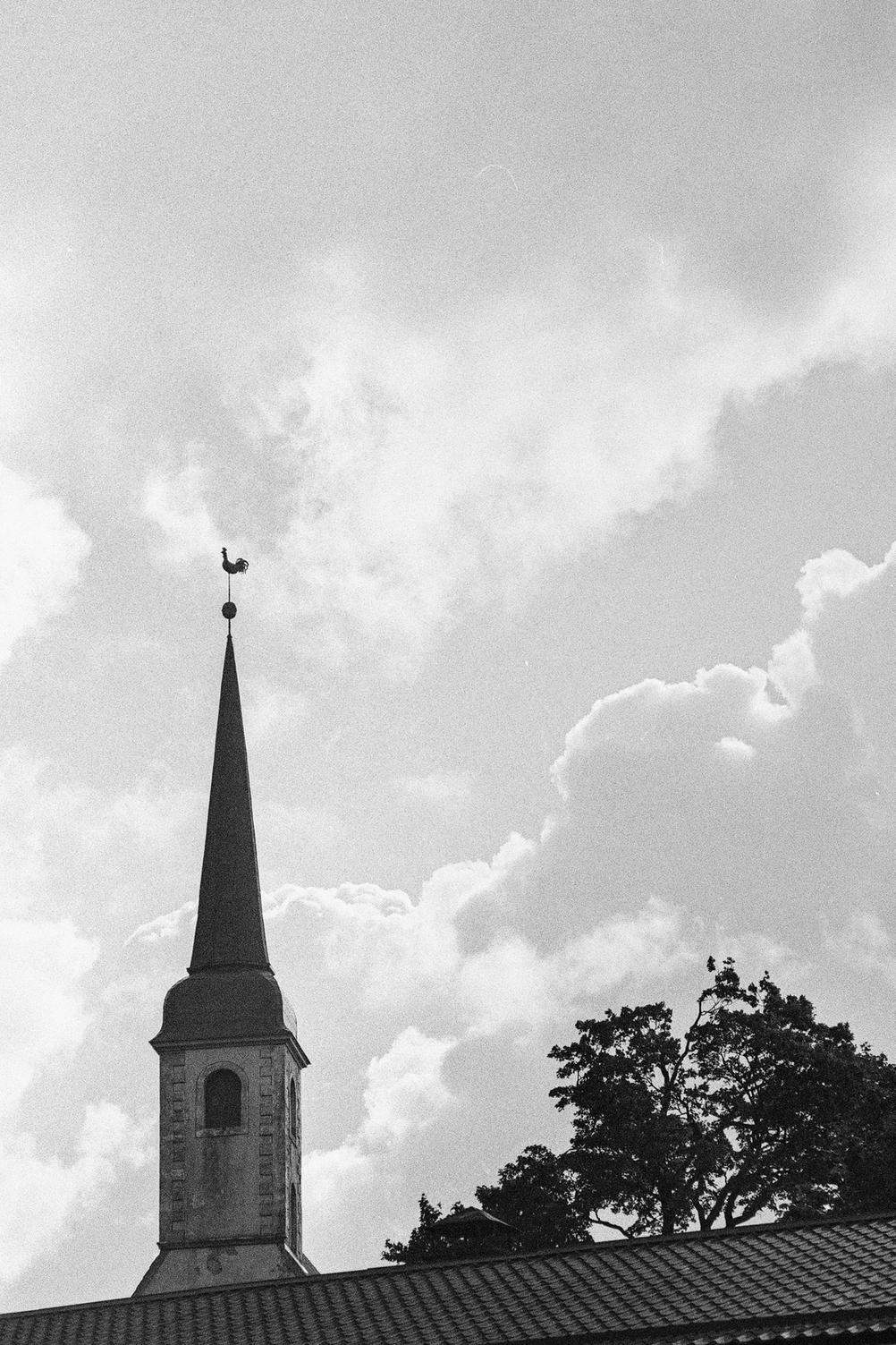 Photo of a church cock with clouds in the background.