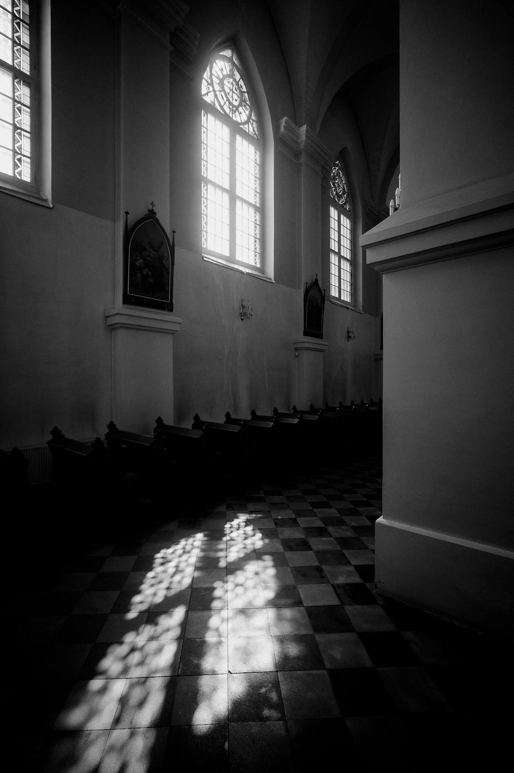 Photo of sun shining through church window on ground.