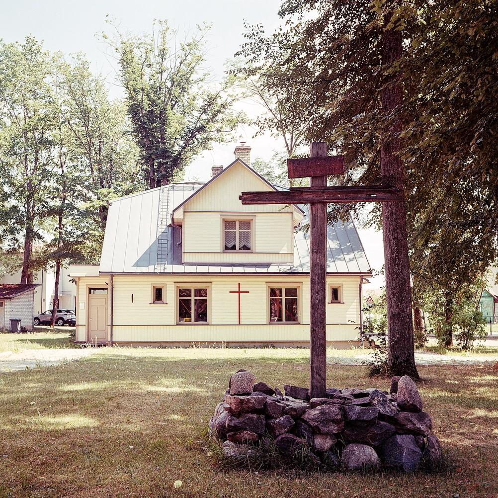 Photo of a big cross in front of a house with another cross.