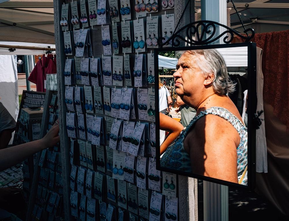 Photo of an older women looking at earrings in market.