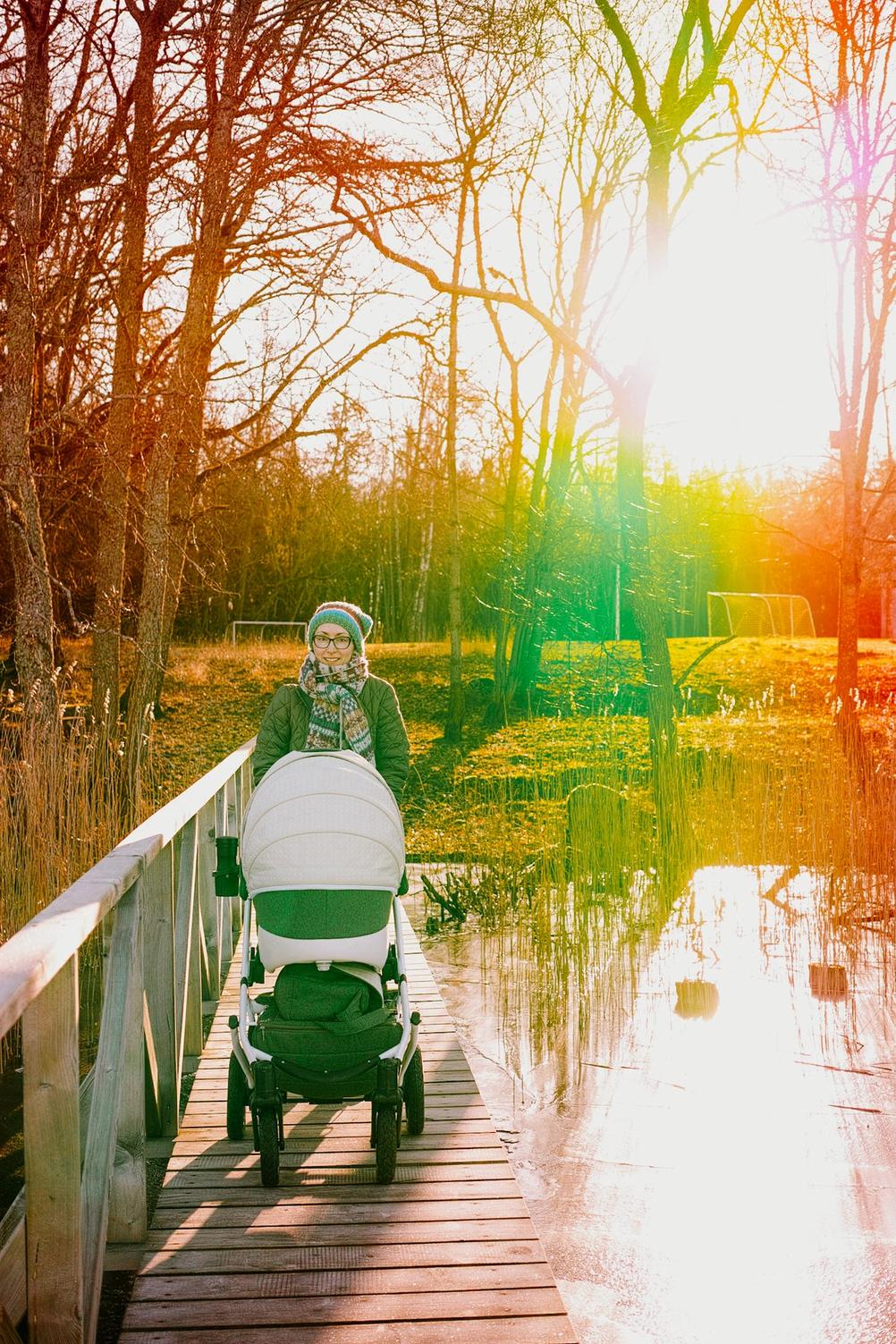 Photo of mother with a stroller against the sun.