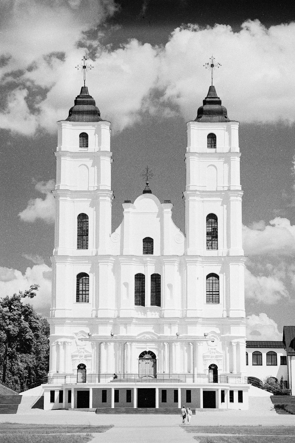 Photo of a white church in front of slightly dramatic clouds.