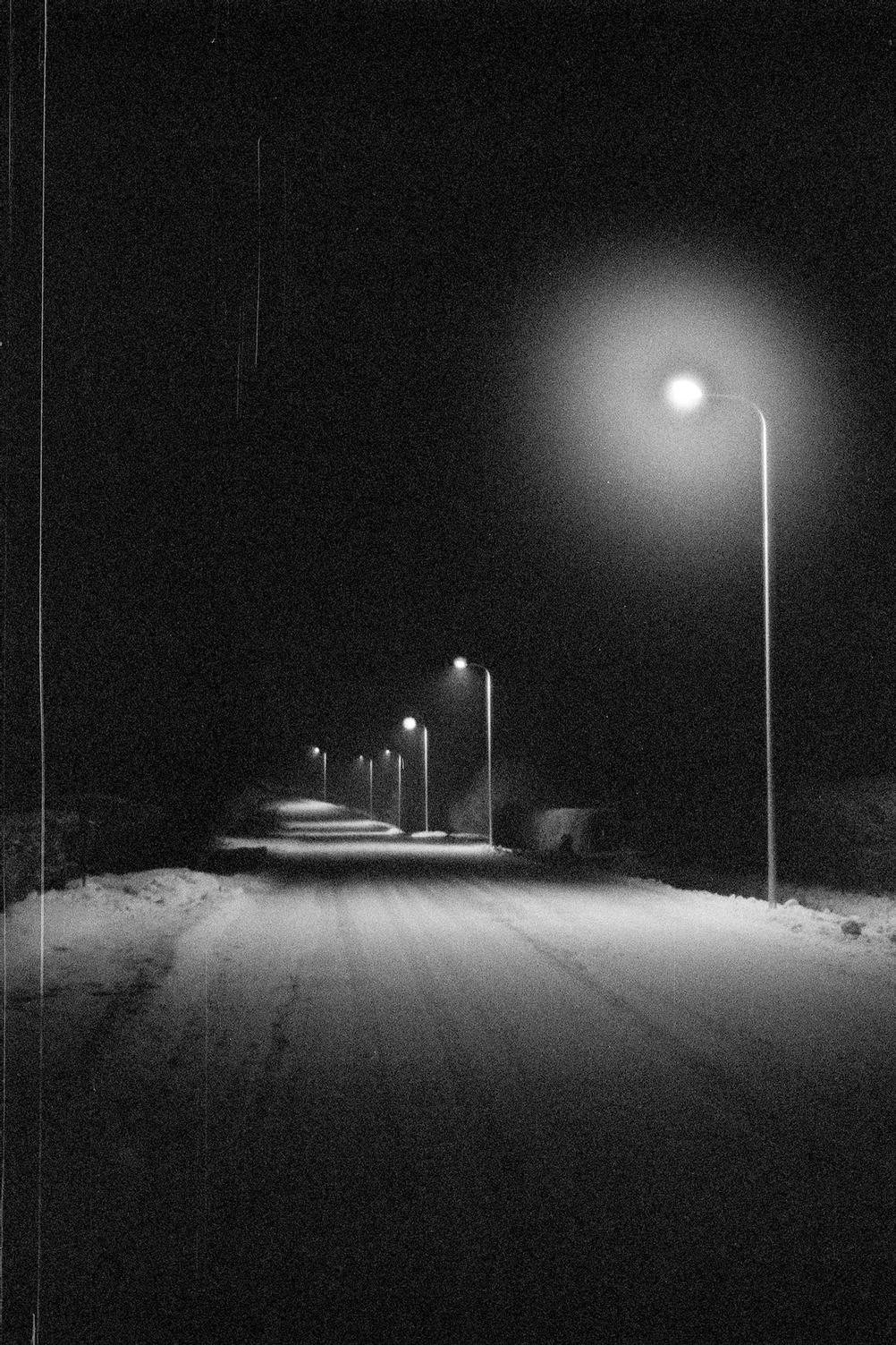 Photo of a street lit up by street lamps.