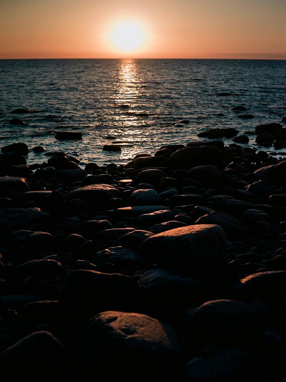Photo of sunset hitting rocks on the beach.