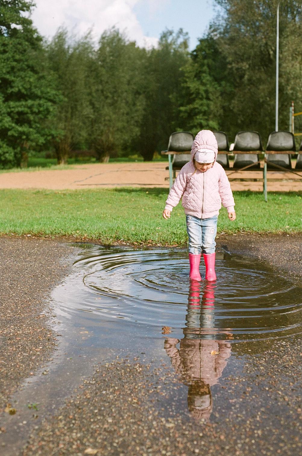 Picture of my daughter standing in rain water with a full sized reflection of her seen in said rainwater.