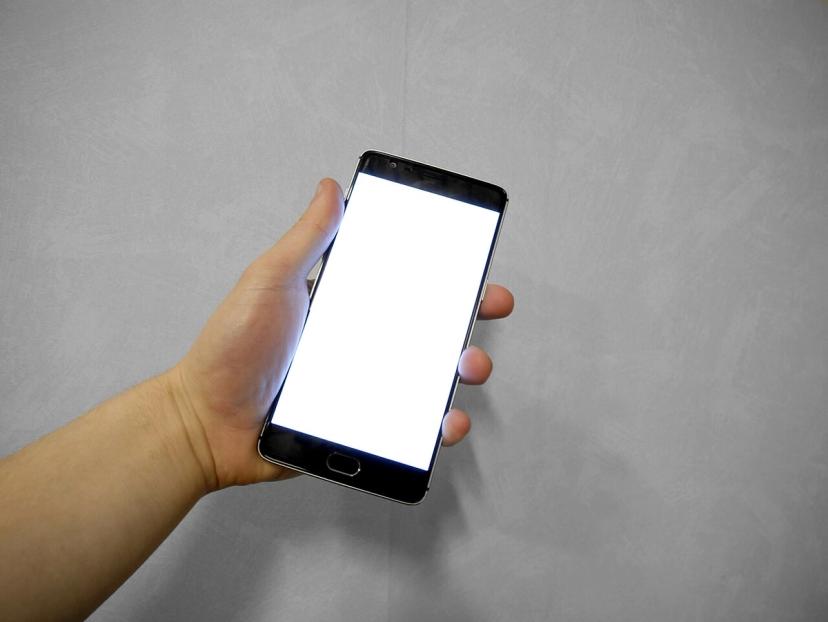 Bàn tay cầm điện thoại thông minh màn hình trắng