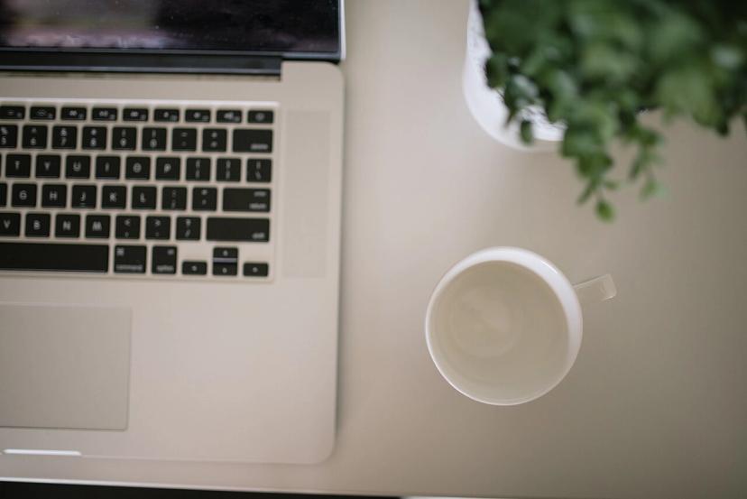 Người làm việc với laptop và ly cà phê trên bàn, minh họa uống cà phê bao nhiêu là đủ