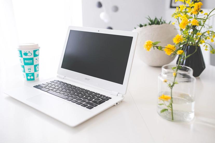 Ly cà phê đặt trên bàn học cạnh laptop và sổ tay