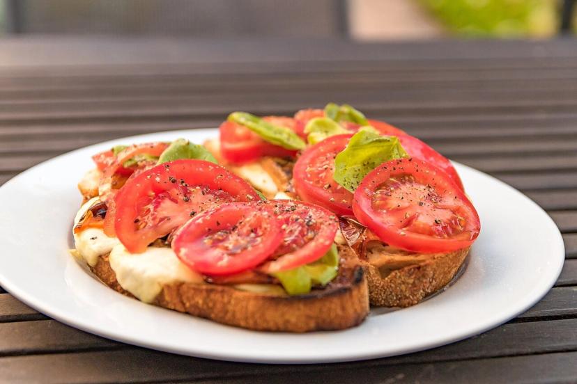 Bánh mì mở với cà chua, ớt và thịt trên bàn, minh hoạ chuyện ăn gì trong khung giờ ăn khi nhịn ăn gián đoạn
