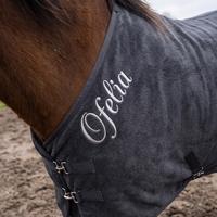Aufgestickter Name auf der Óra Storm — Satinstich in Wollweiss entlang der vorderen Deckenkante