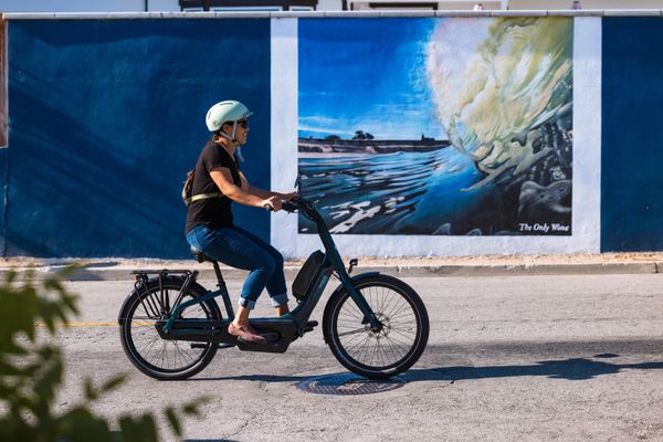 Rider on a Gazelle Easyflow e-bike passing a painted mural