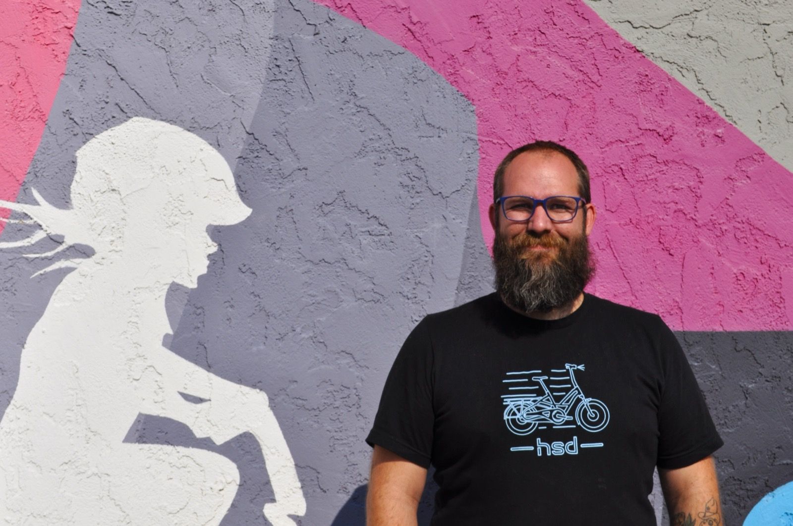 MacKenzie in front of the Hardt Family Cyclery mural