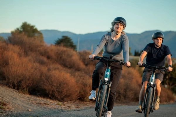 Two riders on Gazelle Ultimate e-bikes on a road through the hills