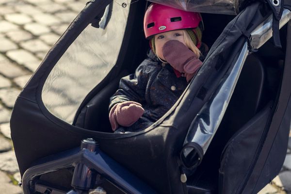 Child in a helmet riding under the canopy of a Larry vs Harry cargo bike