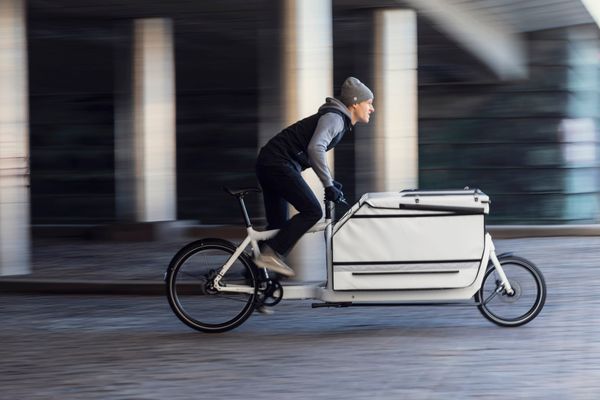 Larry vs Harry Bullitt X with a convoy box, rider passing under a Copenhagen bridge