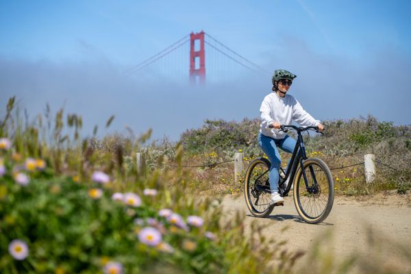 Rider on a Marin Stinson on a coastal path, Golden Gate Bridge in the fog behind