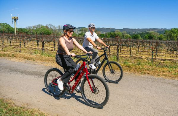 Two riders on Marin Stinson E e-bikes along a vineyard road