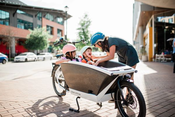 Urban Arrow Family front cargo box with two kids aboard, parent leaning in