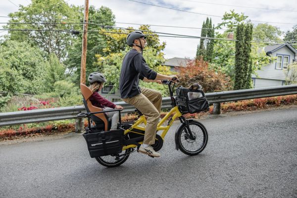 Parent riding a Tern HSD along a residential street with a child on the back and a dog in the front basket