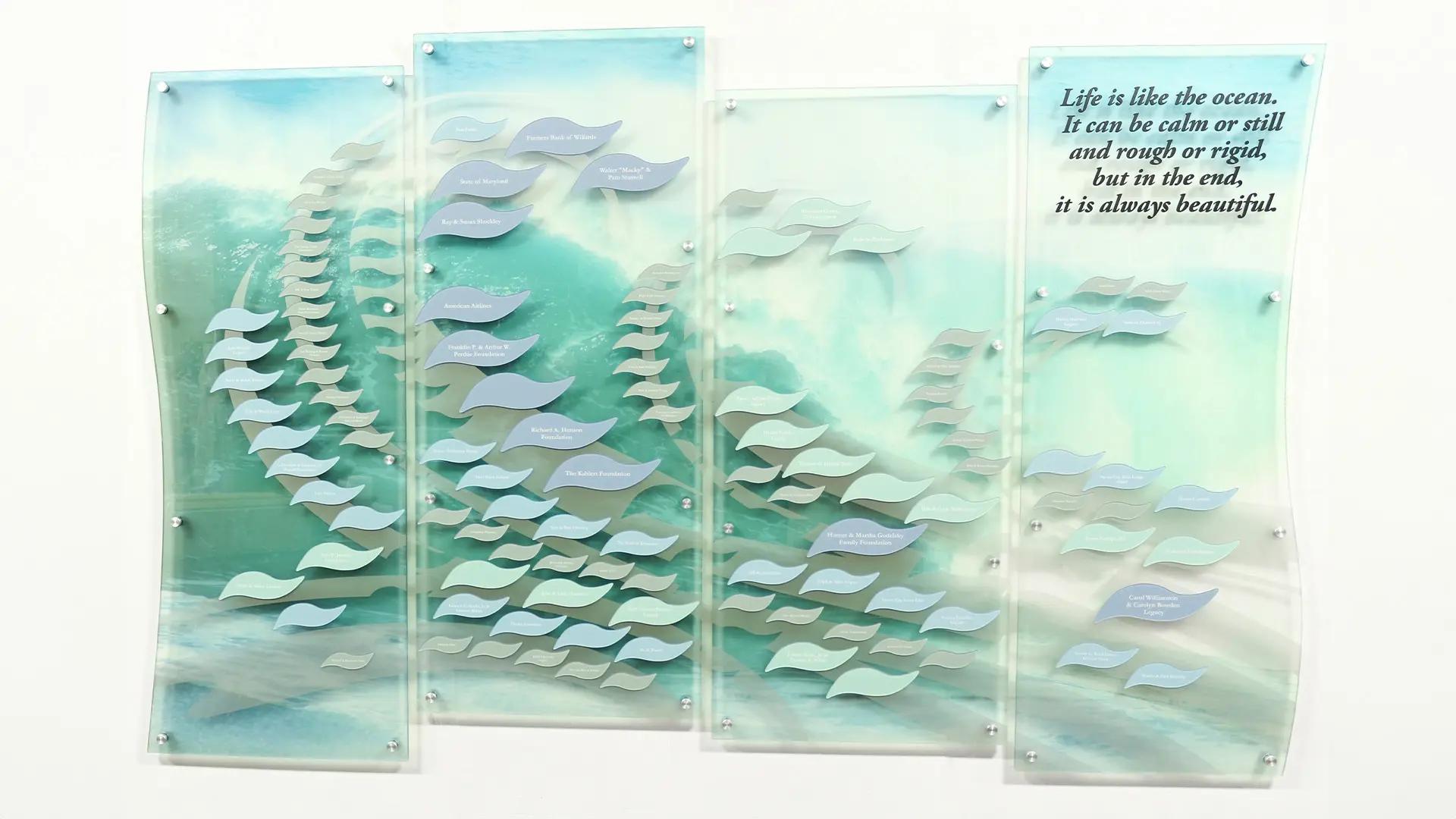 Coastal hospice donor wall with layered acrylic panels and wave-shaped donor tiles inspired by the ocean.