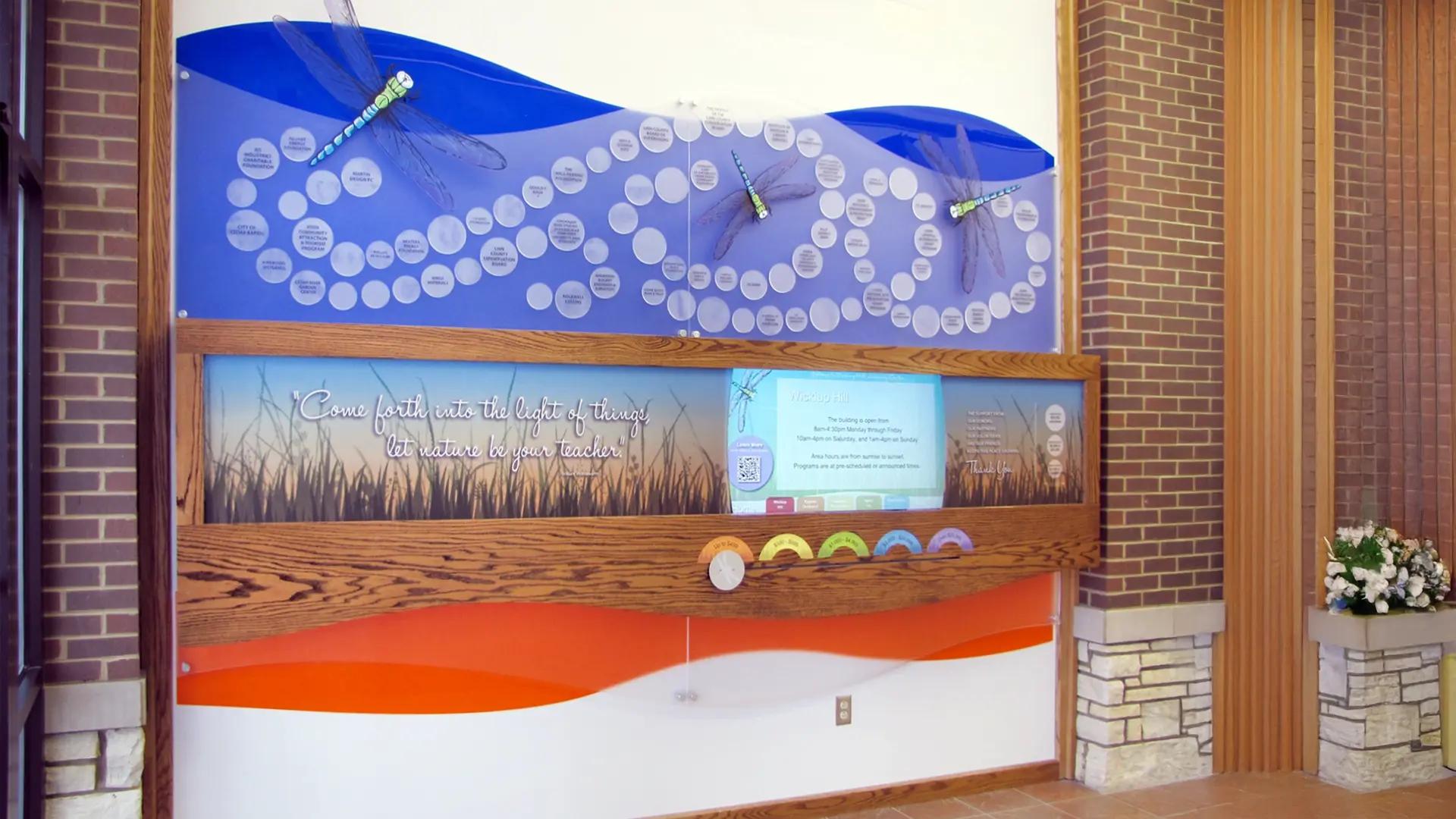 Nature-inspired digital donor wall with engraved donor circles, interactive LED lights, and an integrated digital display framed in wood.