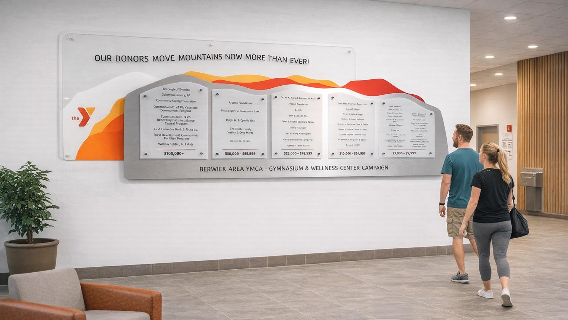 YMCA donor recognition wall with mountain-inspired graphics and tiered donor panels for a community wellness campaign.