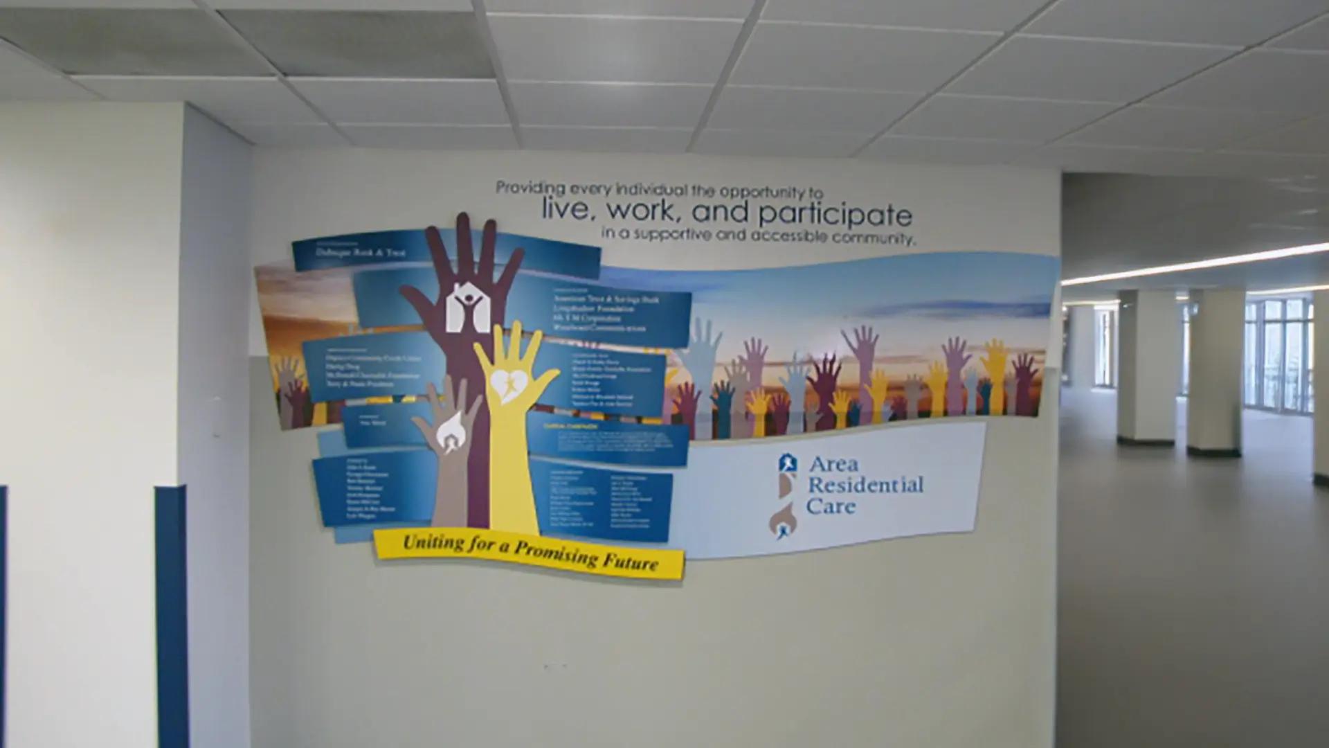 Community donor recognition wall with raised hands graphic and layered panels honoring supporters of Area Residential Care.