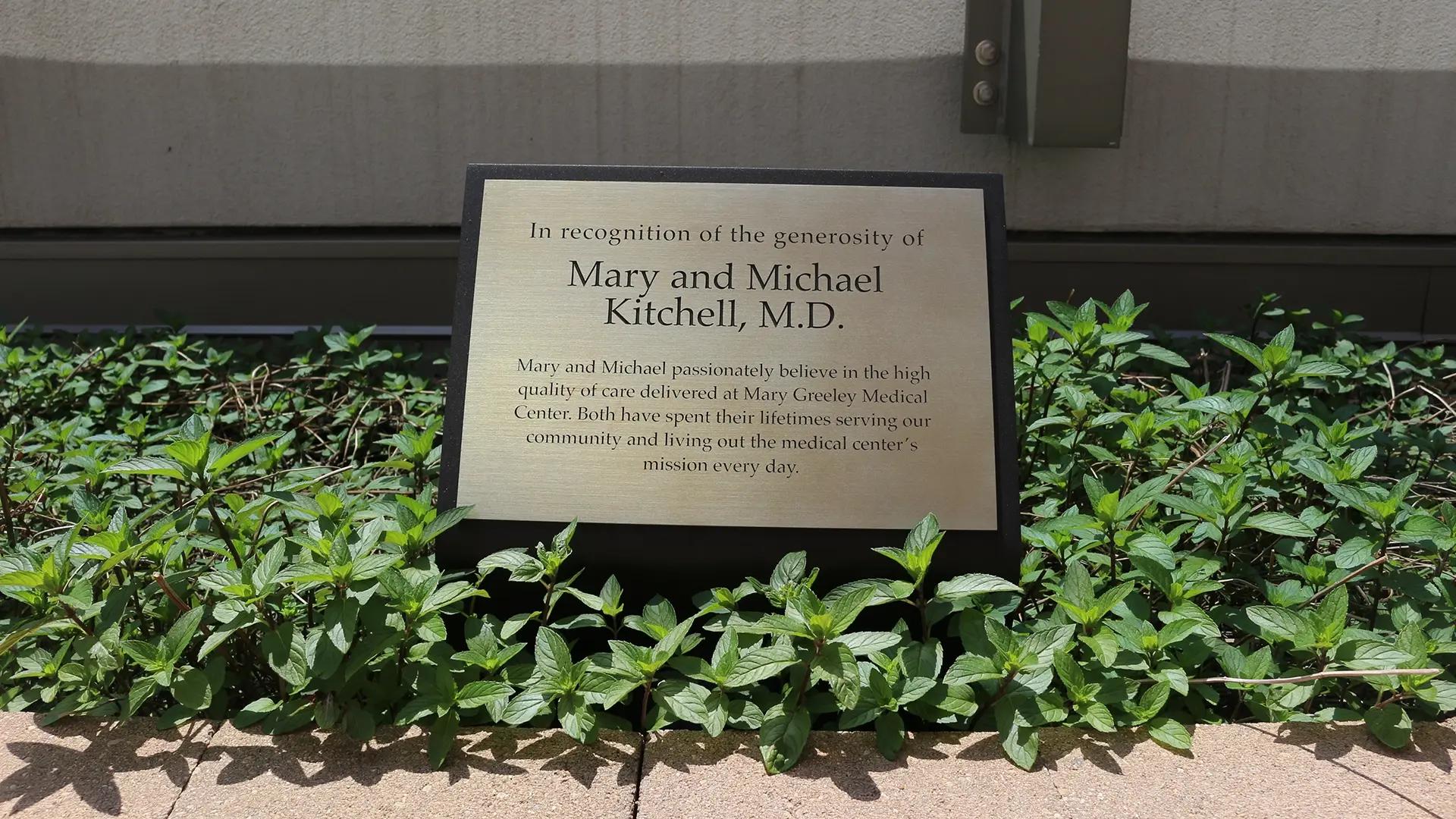 Outdoor donor recognition plaque at Mary Greeley Medical Center set within landscaped greenery honoring philanthropic support.