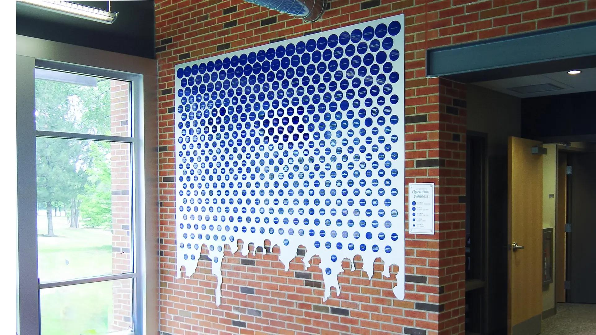 Community Free Clinic tile donor wall with hundreds of blue circular donor tiles mounted on a brick interior wall.