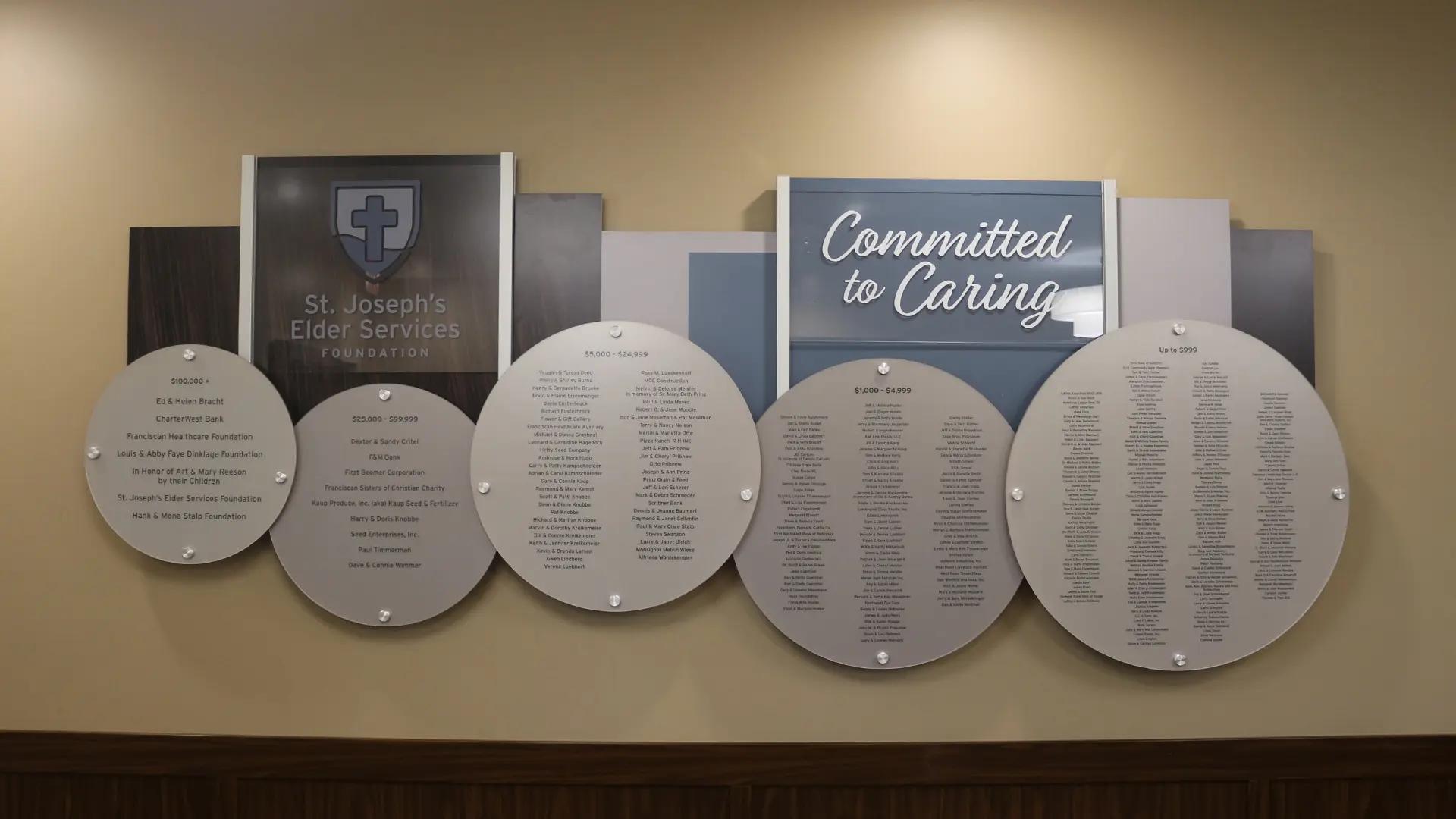 St. Joseph’s Elder Services donor wall using the Rail Wall System with circular donor plaques and mission-focused recognition panels.