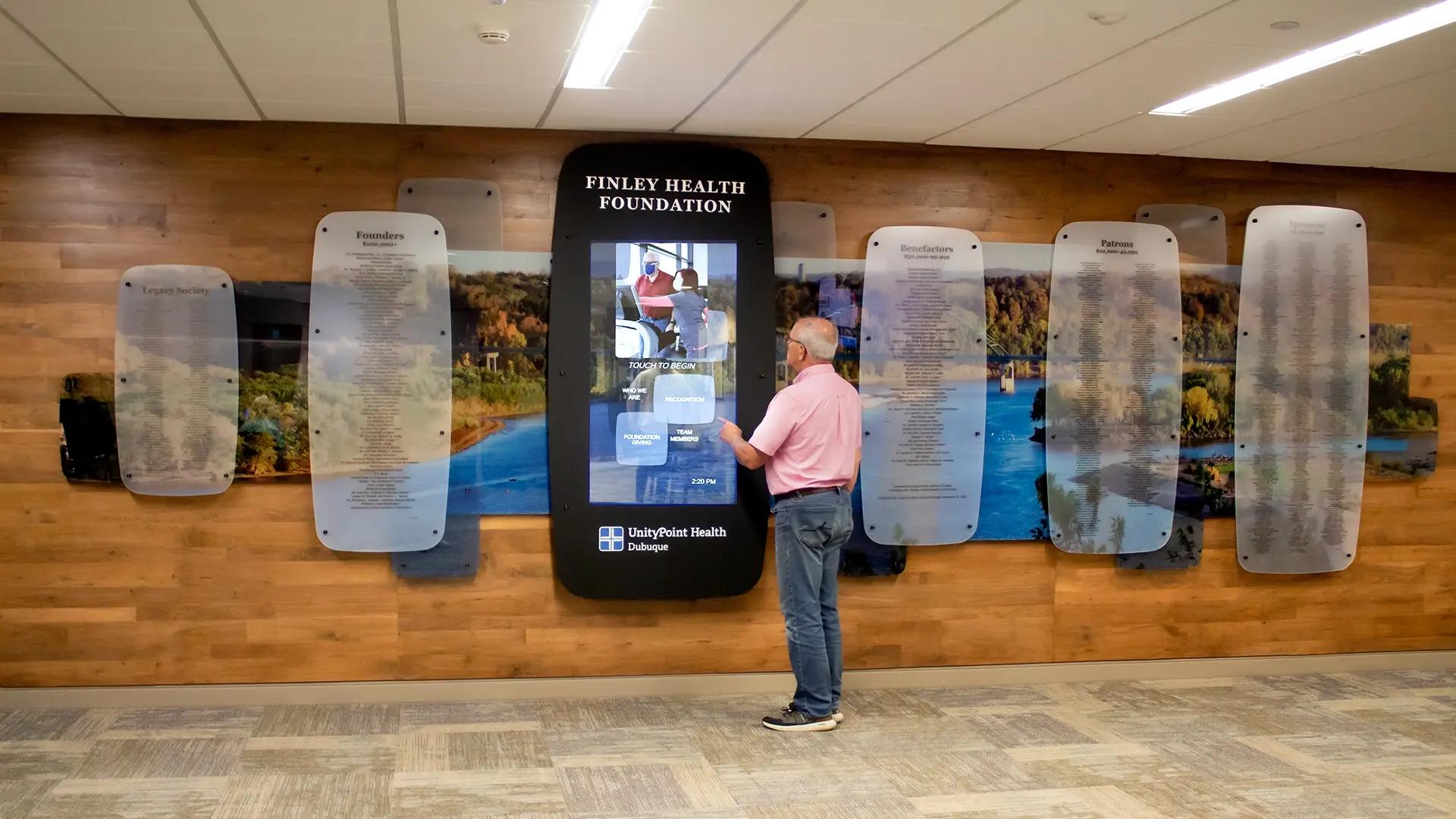 Interactive digital donor recognition wall at Finley Health Foundation with touchscreen honoring donors on layered acrylic panels.